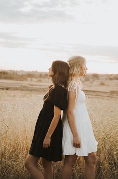 two women standing in the middle of a field with their backs turned to one another