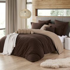 a bed with brown comforter and pillows in a room next to a window,