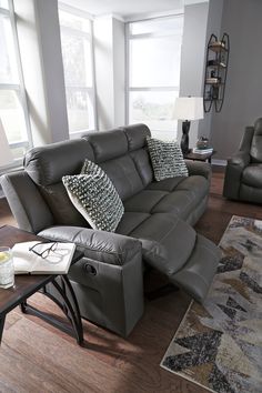 a living room with two recliners and a couch in front of large windows