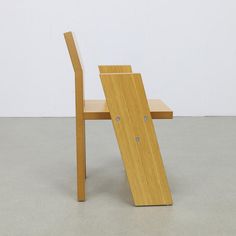 a wooden chair sitting on top of a cement floor next to a white wall and door