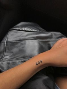 a woman's arm with a small tattoo on her left wrist that reads 444