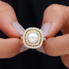 a woman's hand holding a pearl and diamond ring