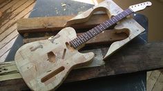 an unfinished guitar is sitting on top of a piece of wood and some other items