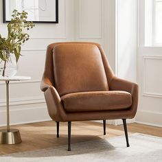 a brown leather chair sitting on top of a wooden floor next to a white rug