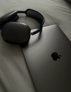 an apple laptop with headphones on top of it next to a pair of sunglasses