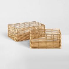 two bamboo baskets sitting next to each other on a white surface with one empty basket in the middle