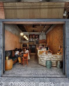 an open garage door shows people sitting at tables and chairs in the room with exposed brick walls