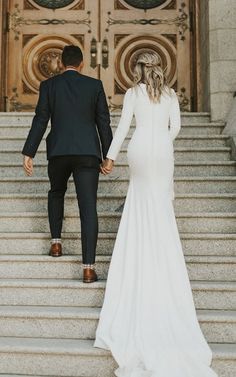 a bride and groom walking down the stairs