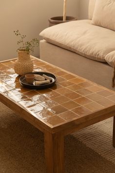 a coffee table with a plate on it in the middle of a living room next to a couch