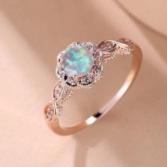 an opal and diamond engagement ring on a white background with the light shining through it