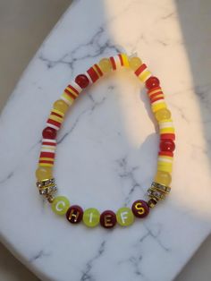 Kansas City Chiefs clay bead bracelet handmade with elastic stretch thread with the red letter beads and gold letters.  Red, white and yellow. Red Heishi Bead Jewelry With Letter Beads, Red Heishi Beads Jewelry With Letter Beads, Yellow Heishi Beads Bracelets With Letter Beads, Yellow Heishi Bracelets With Letter Beads, Clay Bead Bracelet, Sparkle Bracelet, Clay Bead, Bracelet Diy, Letter Beads