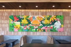 a colorful painting hangs on the wall in a restaurant