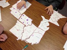 three children sitting at a table making maps