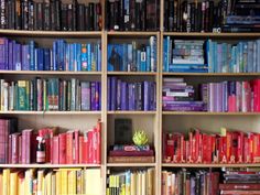 a bookshelf filled with lots of different colored books on top of wooden shelves