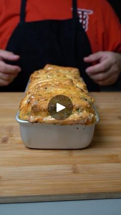 a person standing in front of a casserole dish on a wooden cutting board