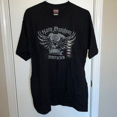 a black t - shirt hanging on a door with an eagle and motorcycle design on it