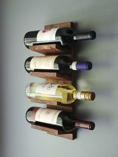 several bottles of wine are lined up on a wooden shelf against the wall in front of a white wall