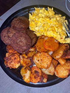 a black plate topped with breakfast foods and a fork