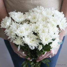 a woman holding a bouquet of white flowers