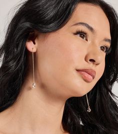 a woman with long black hair and earrings on her head looking off to the side