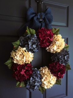 a wreath with red, yellow and blue flowers is hanging on the front door handle