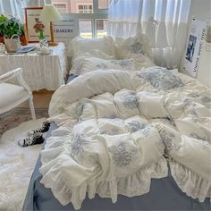 an unmade bed in a bedroom with white furniture and curtains on the window sill