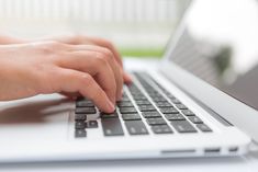 a person typing on a laptop computer with their hands resting on the keyboard and mouse