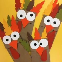 three turkeys made out of paper with eyes and leaves on them sitting in front of a yellow background