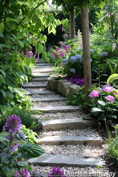 a garden path with stepping stones and flowers on each side, surrounded by greenery