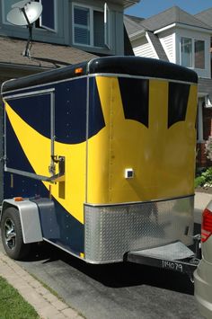 a yellow and blue trailer parked in front of a house