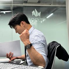 a man sitting at a desk in front of a laptop computer with his hand on his face