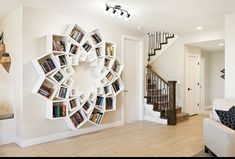 a living room filled with furniture and a book shelf next to a stair case full of books