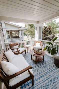 a porch with chairs, tables and pillows on the front porch overlooking an outdoor living area