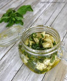 a jar filled with pasta and spinach on top of a wooden table