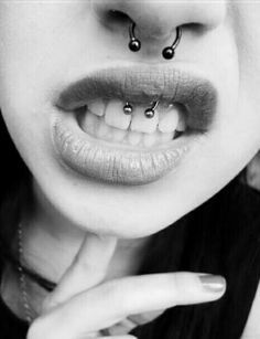 a woman with piercings on her nose and lip is posing for the camera in black and white