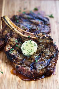 two steaks on a wooden cutting board with sauce