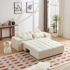 a white couch sitting on top of a rug in a living room next to a window