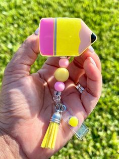 a hand holding a small yellow and pink object in it's left hand with other items attached to it