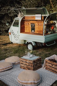 an old camper van is parked in the grass with some pillows on it and other items