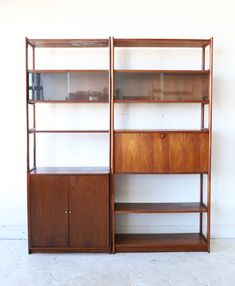 two wooden bookshelves sitting next to each other on top of a white wall