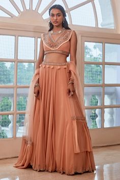 Rose gold blouse with boho embroidered V-neckline and sleeveless. Comes with scallop edged lehenga and ruffle dupatta.
Component: 3
Embroidered
Neckline: V-Neck
Sleeve Length: Sleeveless
Color: Peach
Mirror, resham, cutdana and stone embroidery
Sheer back
Embroidered waistband with tassels
Embroidered ruffle dupatta
Closure:
Lehenga: Drawstring at the side - Aza Fashions Boho Lehenga, India Traditional Dress, Peach Embroidery, Rose Gold Boho, Rose Gold Fabric, Ruffle Dupatta, Gold Lehenga, Indian Bridesmaids, Western Dresses For Women