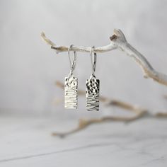 "Dainty hammered silver rectangular tag earrings, paired with secure lever-back ear wires. Hand hammered for added sparkle, no two are exactly alike. All in solid sterling silver metal for long lasting quality. * Overall earring length is about 1.1 inches (standard) or 1.3 inches (lever-back). * Tag dangles are about 0.65 inch by 0.27 inch. * All components are solid sterling silver. * Standard earwires with clear stoppers or hinged lever-back earwires. * Handcrafted with love in Alaska. * Beaut Silver Earring Ideas, Minimalist Hammered Dangle Earrings, Simple Silver Hammered Earrings, Elegant Silver Hammered Earrings, Minimalist Silver Hammered Earrings, Silver Hammered Sterling Silver Linear Earrings, Silver Jewelry Diy, Minimal Earrings, Hammered Earrings