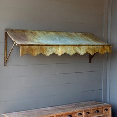 an old rusted metal awning hanging from the side of a building next to a wooden dresser