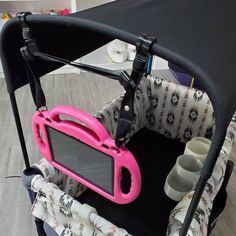 a baby buggy with pink handles and cup holders on the seat, next to other items