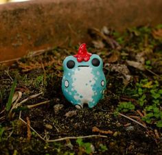 a blue and white frog with a red bow on its head sitting in the grass