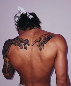 the back of a man's body with tattoos on his arms and hands behind him