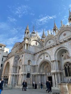 people are walking around in front of an old building with many spires and arches