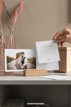 a desk with a calendar, photos and flowers on it