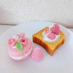 two pieces of bread with pink frosting and strawberries on them sitting next to one piece of cake