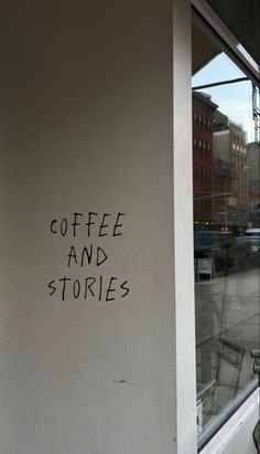 the words coffee and stories are written in black ink on a white wall next to a window